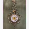 Charmante horloge murale en laiton avec décor floral et détail suspendu