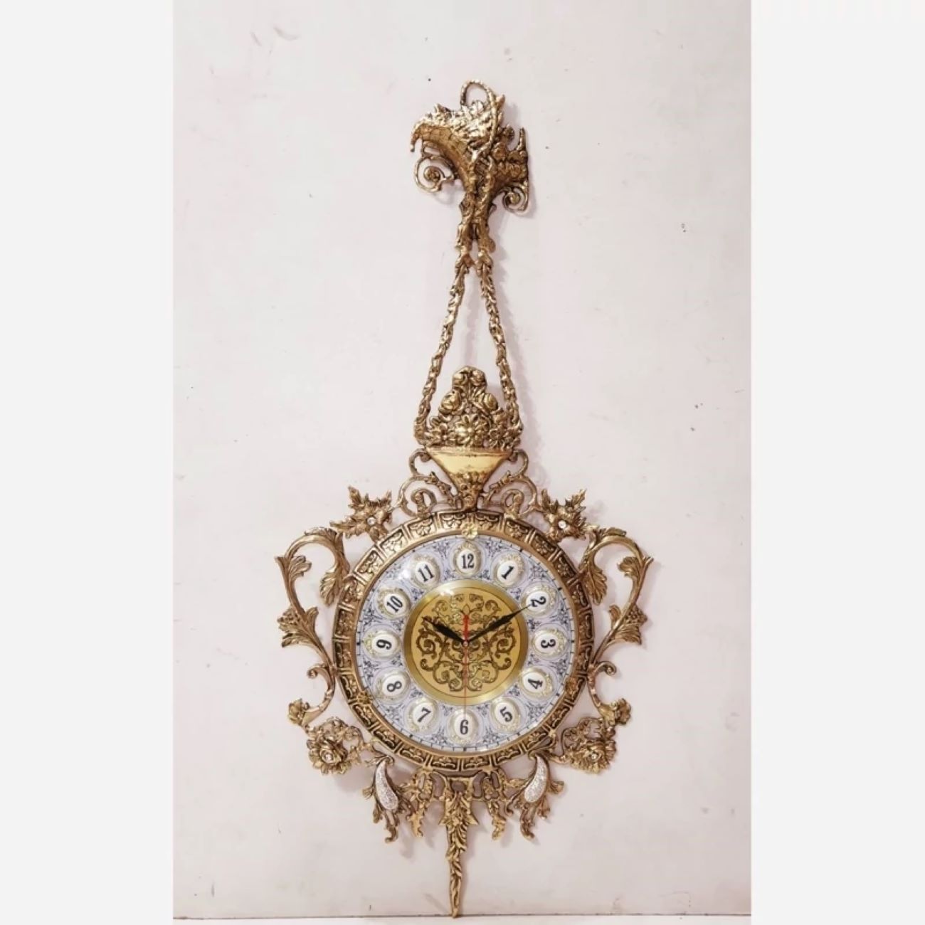 Charmante horloge murale en laiton avec décor floral et détail suspendu
