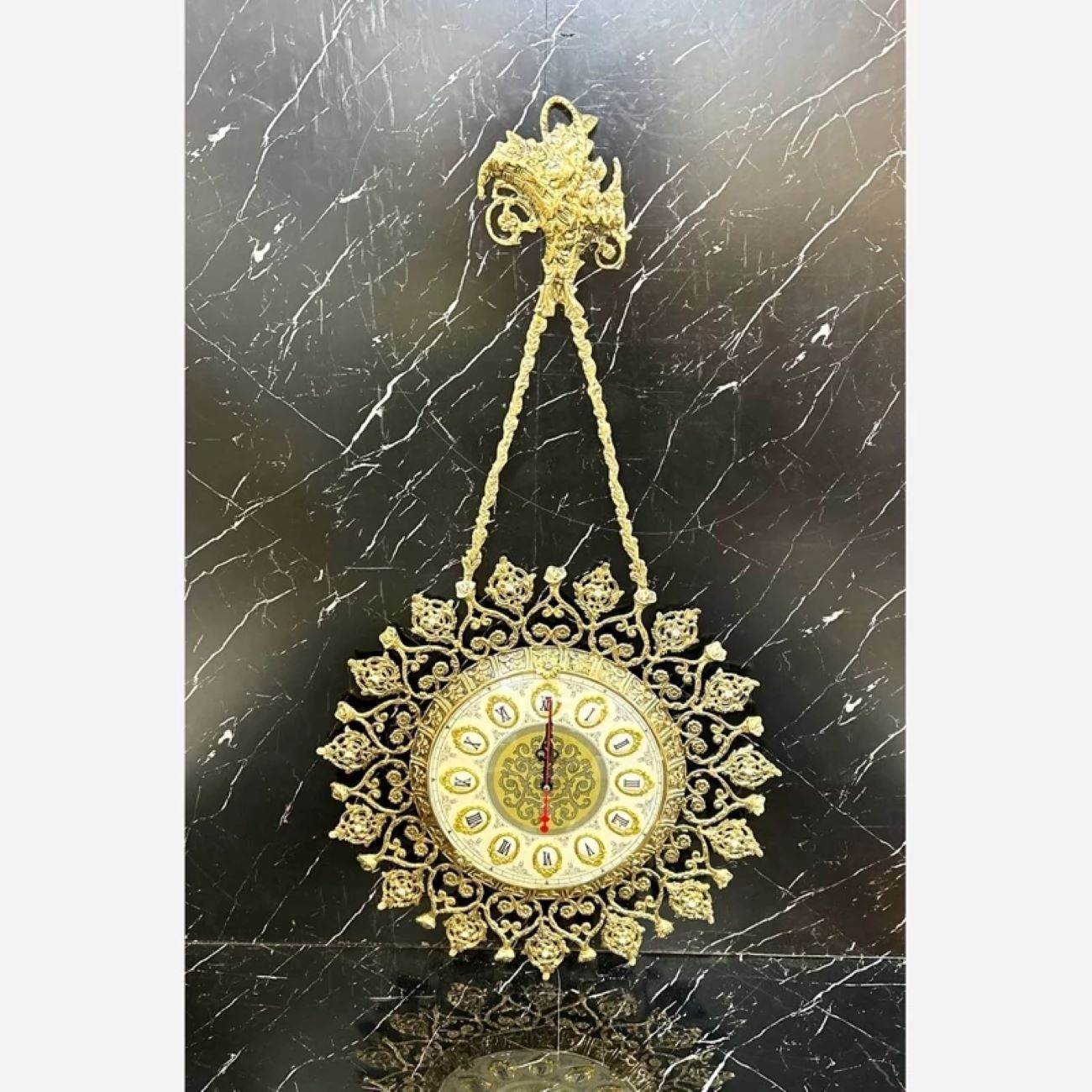 Charmante horloge murale en laiton avec décor floral et détail suspendu